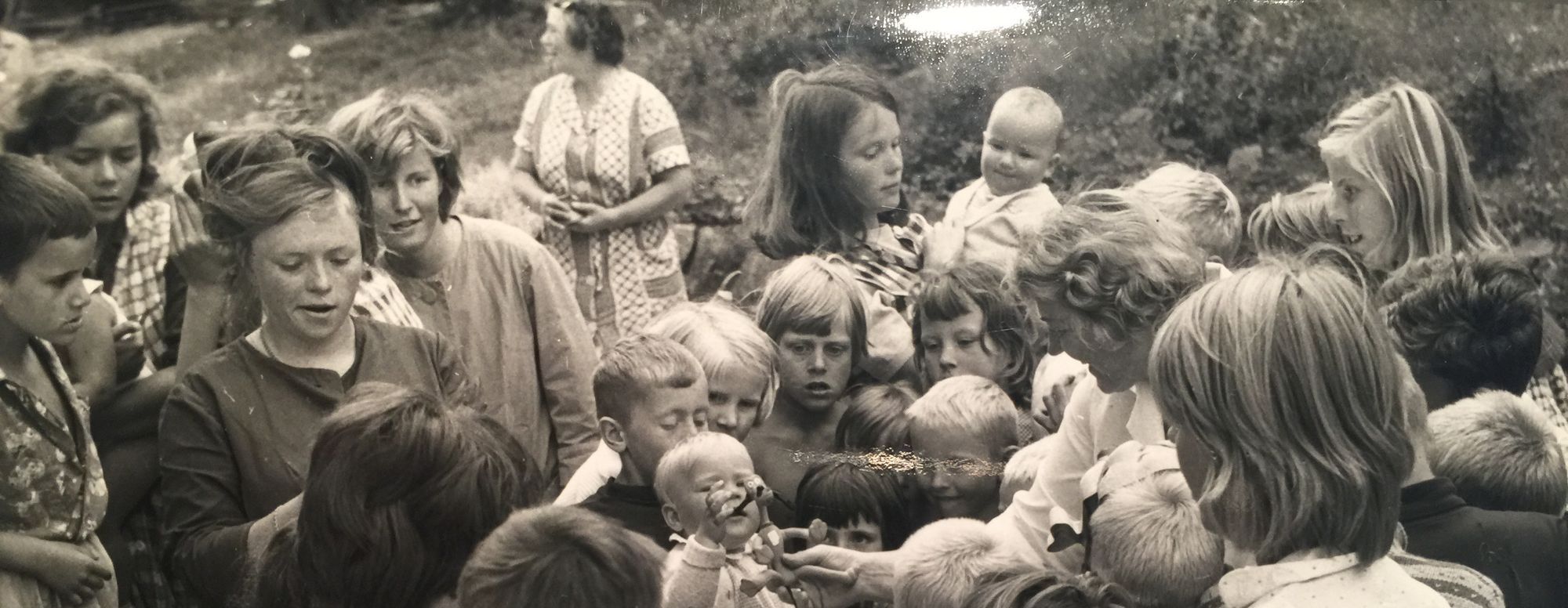 Historisk bilde i svart hvitt. Barn som er samlet rundt en leke.